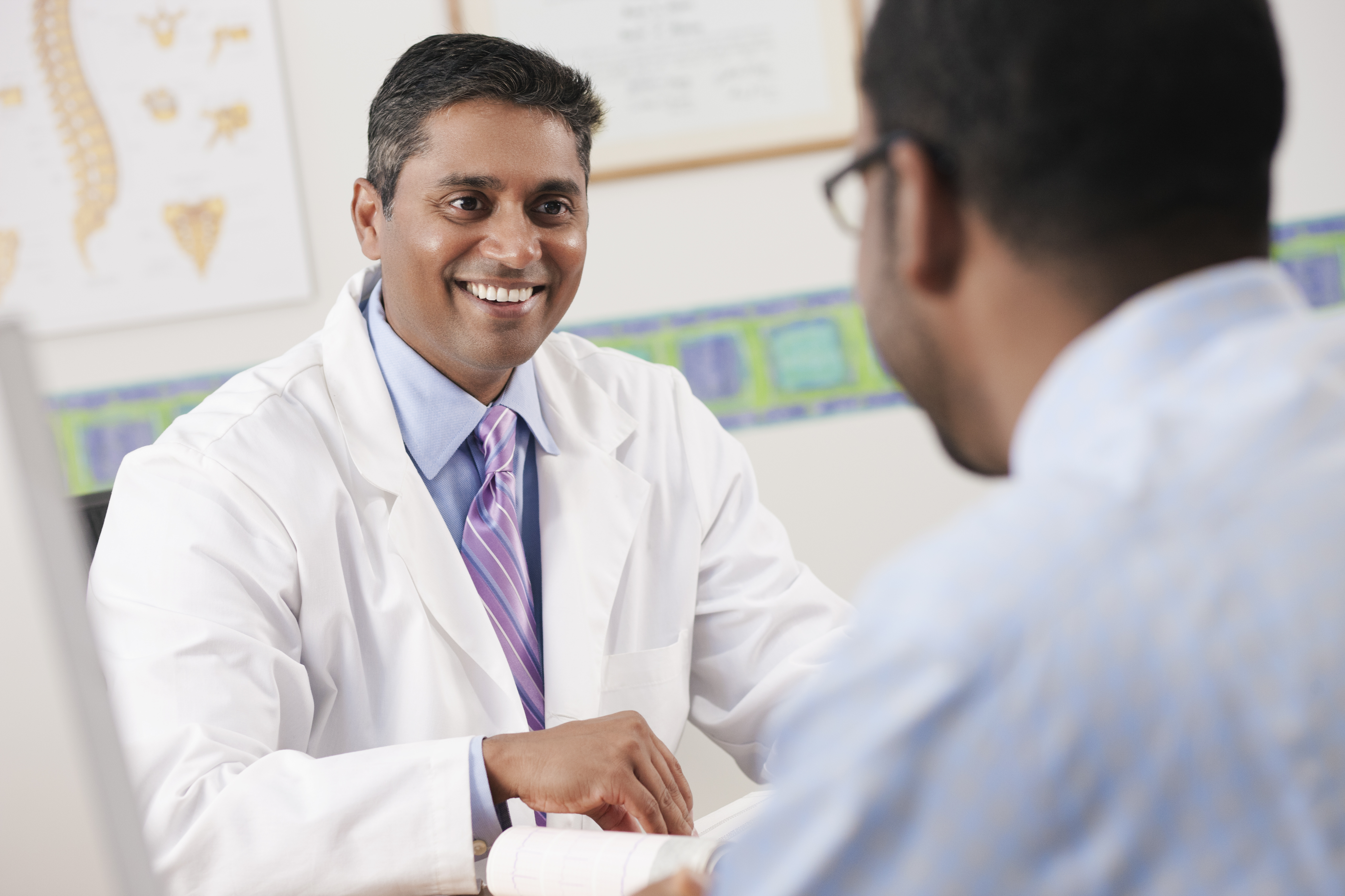 Médico sonriente sentado frente a un paciente