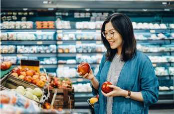 A woman selects healthy fruit at the grocery store. 