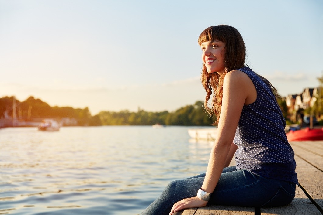 mujer sonriente sentada junto al agua