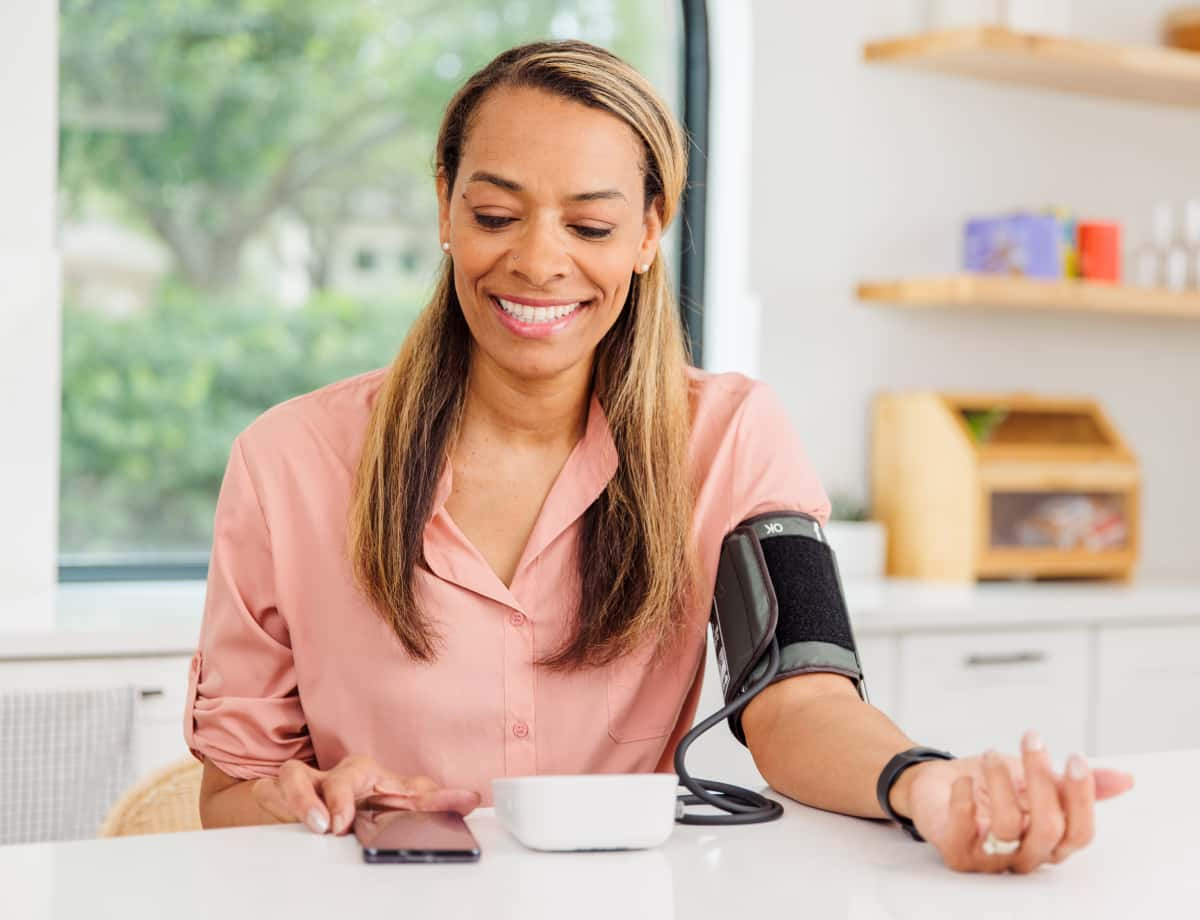 Woman checking her blood pressure using Hello Heart monitor.