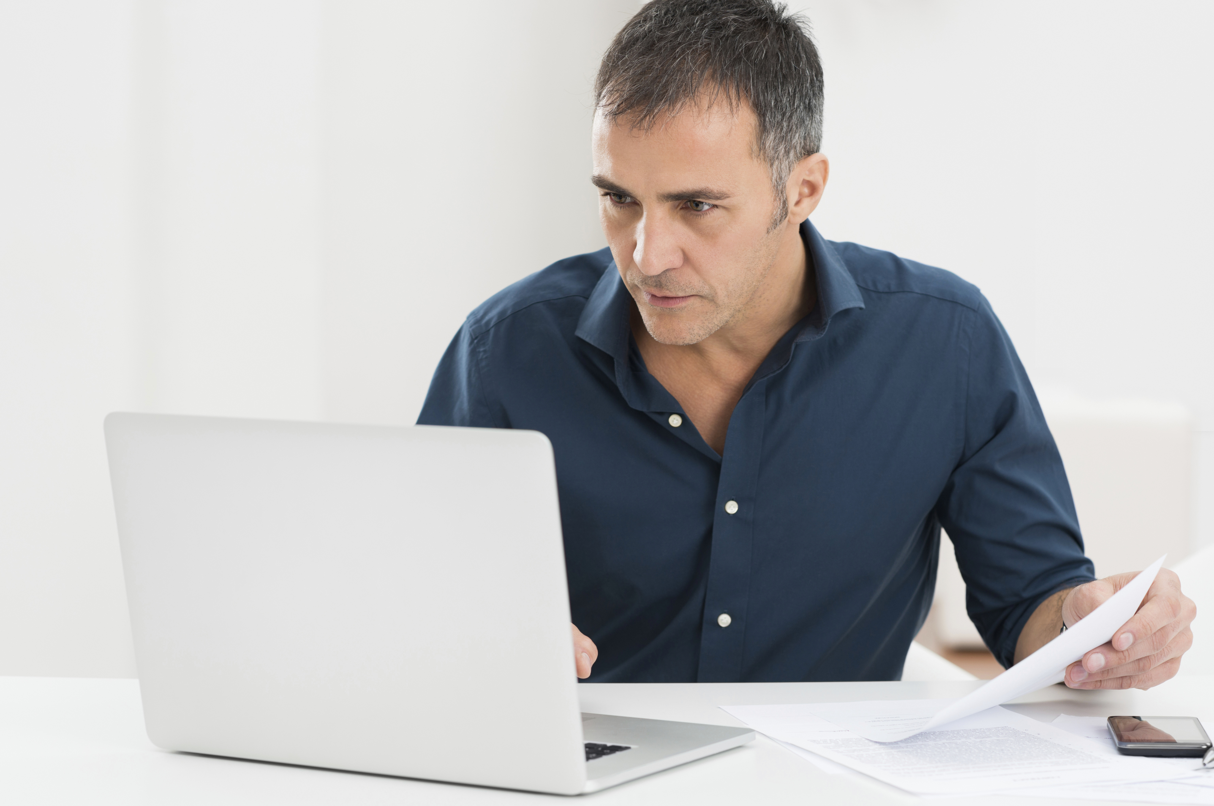 Hombre adulto revisando documentos en su computadora portátil