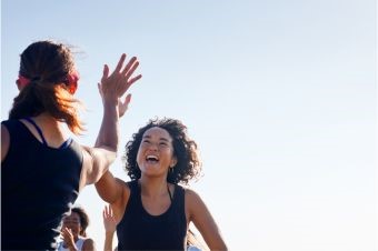 Two smiling women high fiving during an outdoors activity