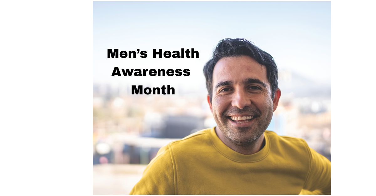 Smiling man in a yellow shirt stands outdoors with blurred cityscape behind him; bold text reads "Men’s Health Awareness Month.