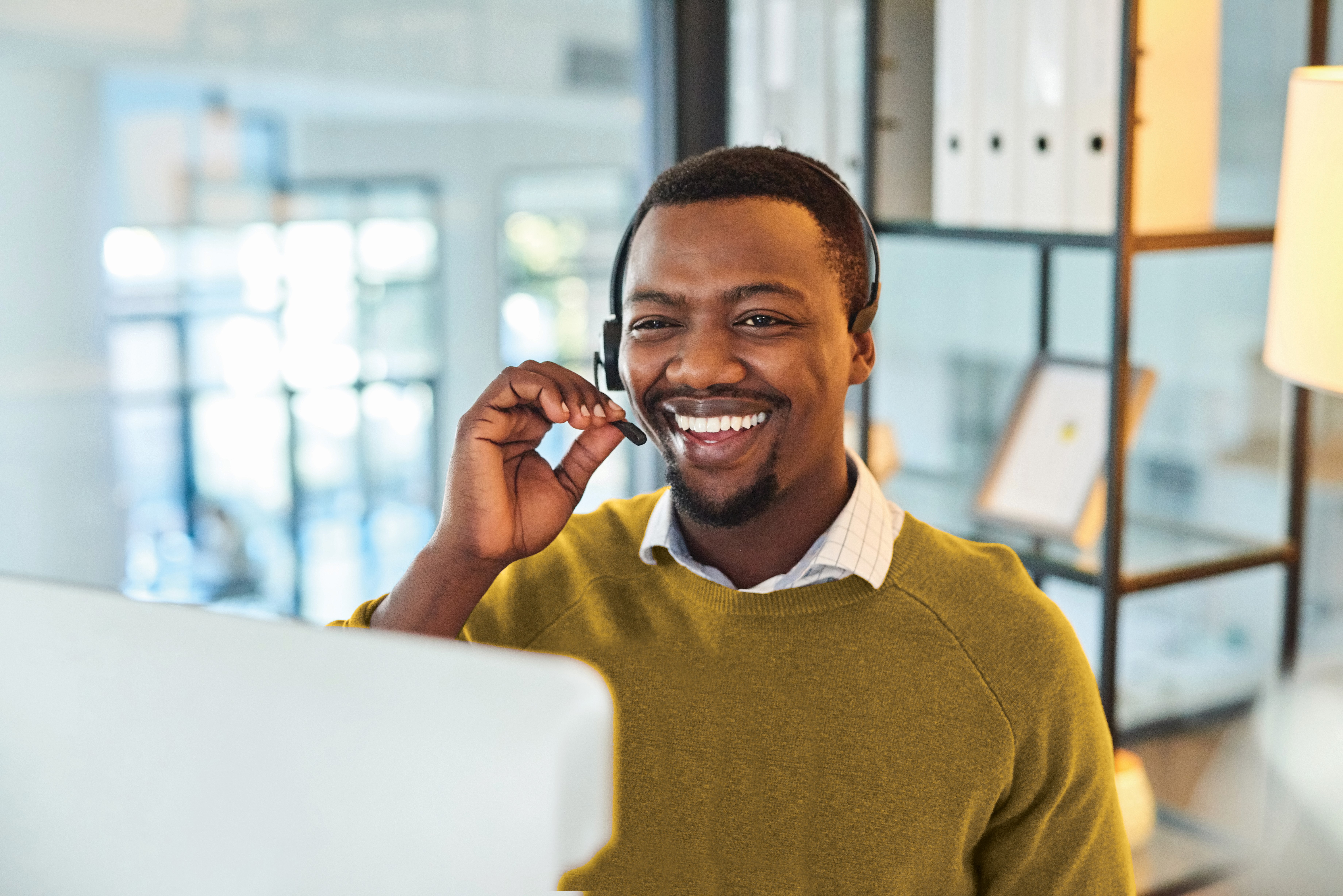 Image of man sitting at computer talking on a headset.
