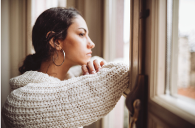 Woman gazing out the window with a sad expression